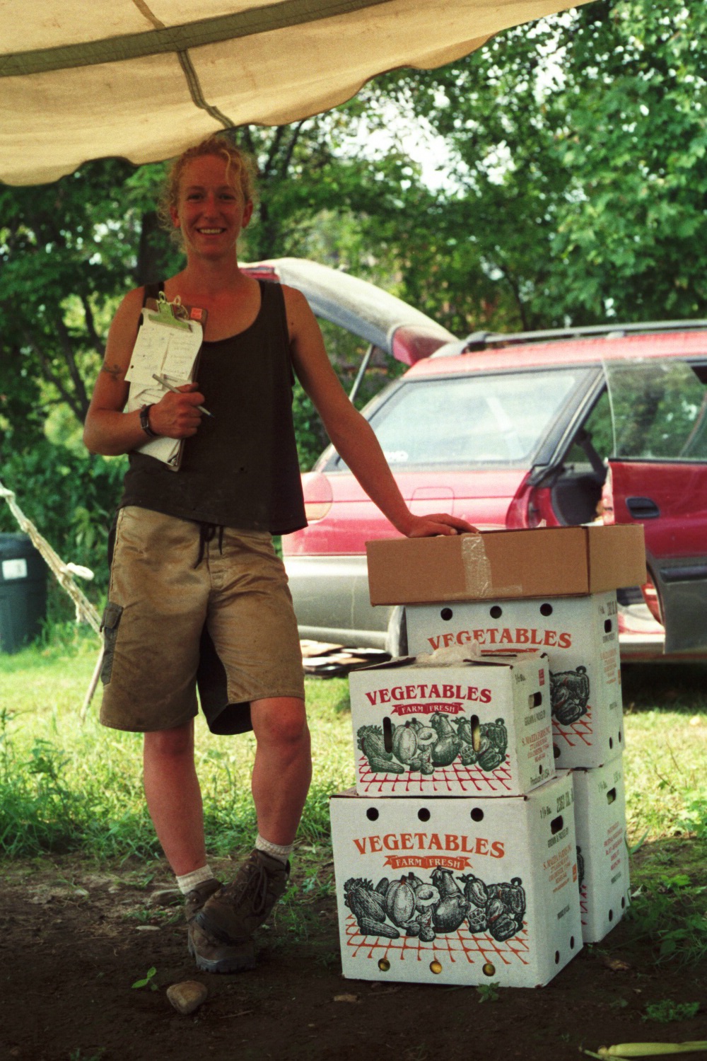 Theresa with The Last Harvest woman with clipboard stand next to boxes full of produce